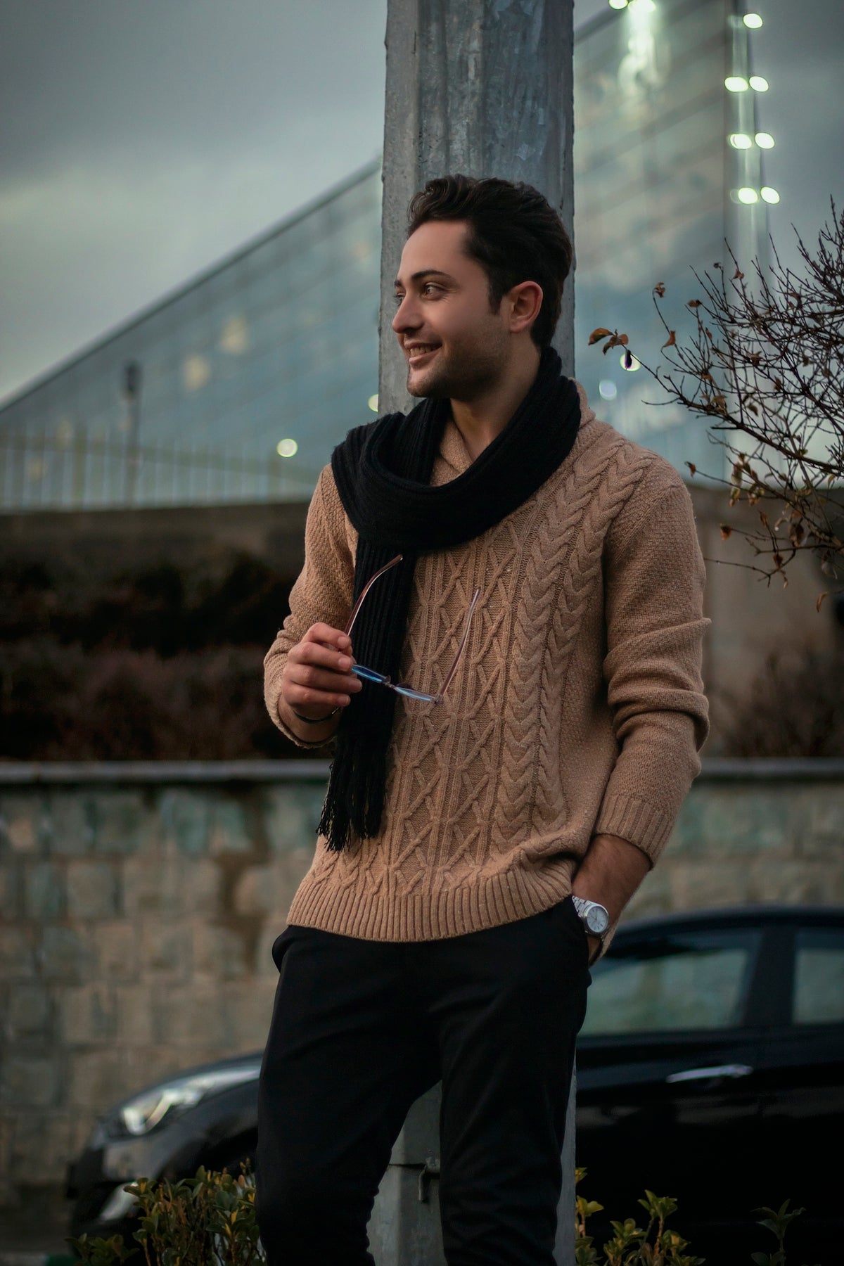 a man standing next to a pole wearing a scarf