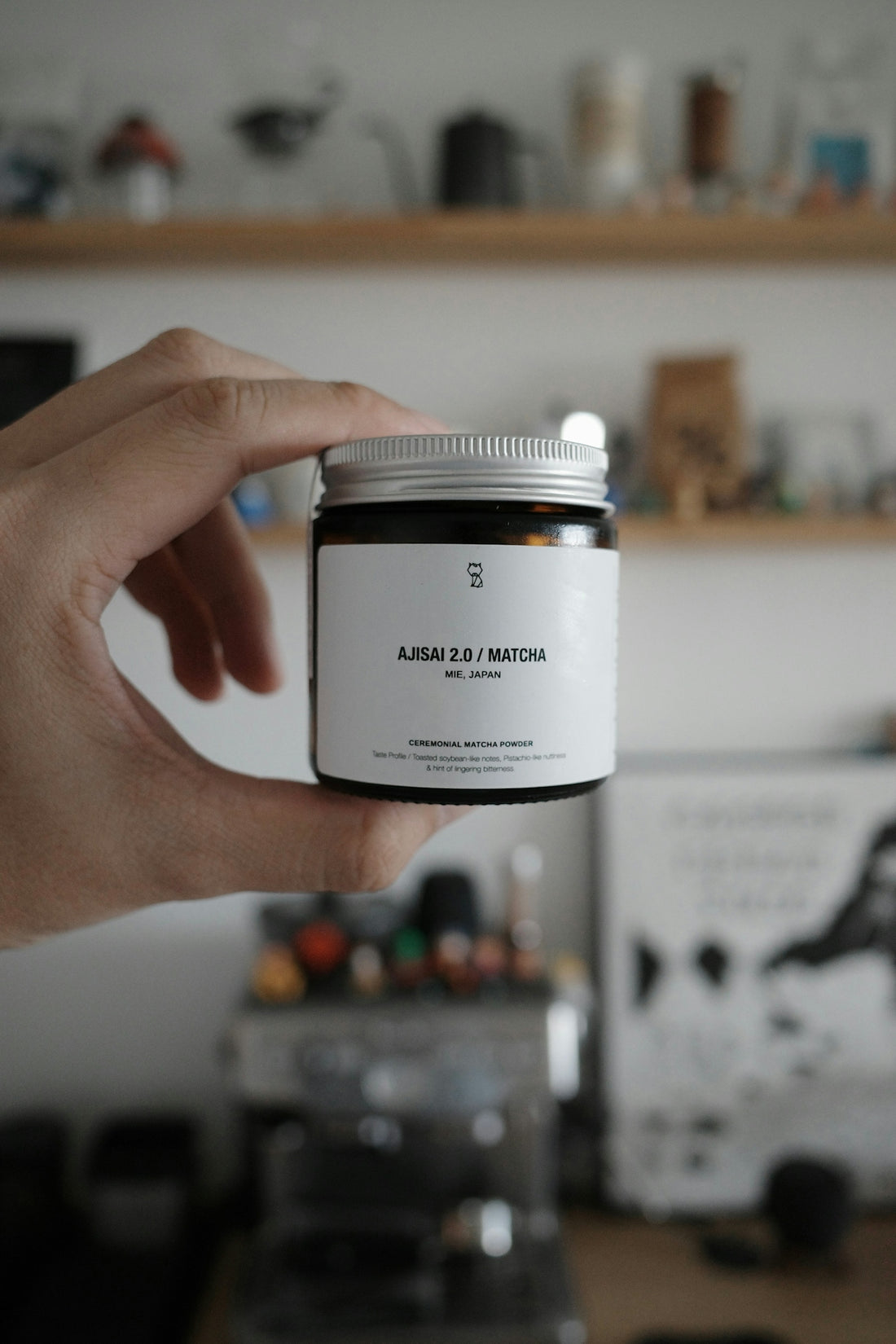 Hand holding a jar of matcha powder